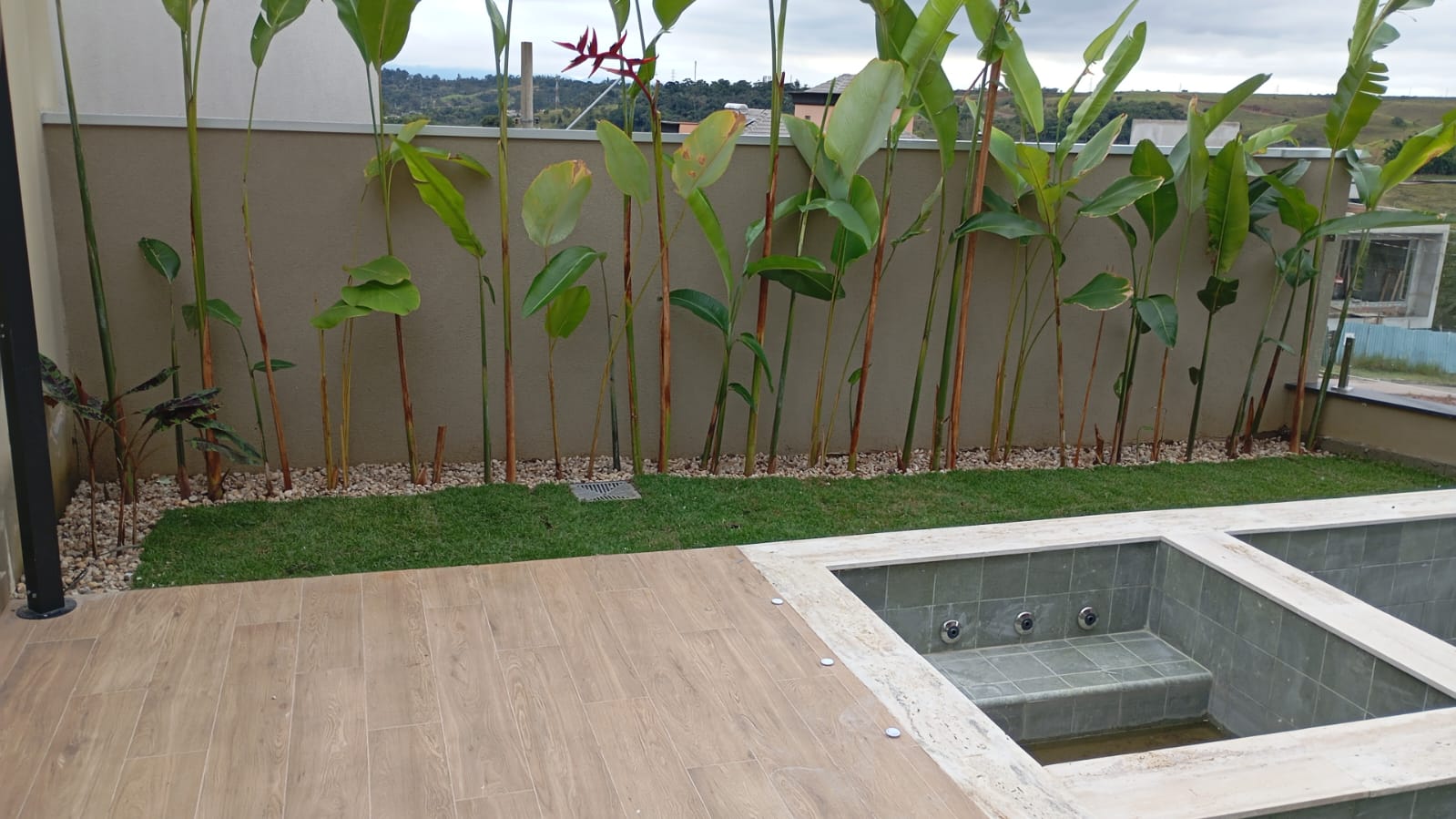 Área externa com calçamento e jardim lateral